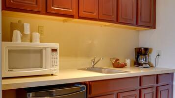 A kitchen with wooden cabinets, a microwave, a sink, and a coffee maker.