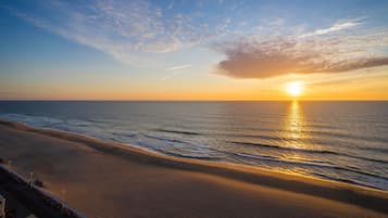 Una playa con un atardecer, mar tranquilo y cielo despejado.