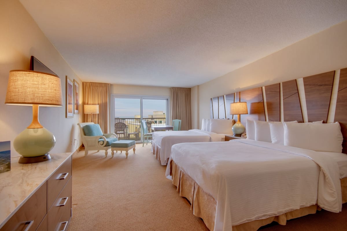 Une chambre d’hôtel avec deux lits, un bureau, des chaises et une vue sur la ville.