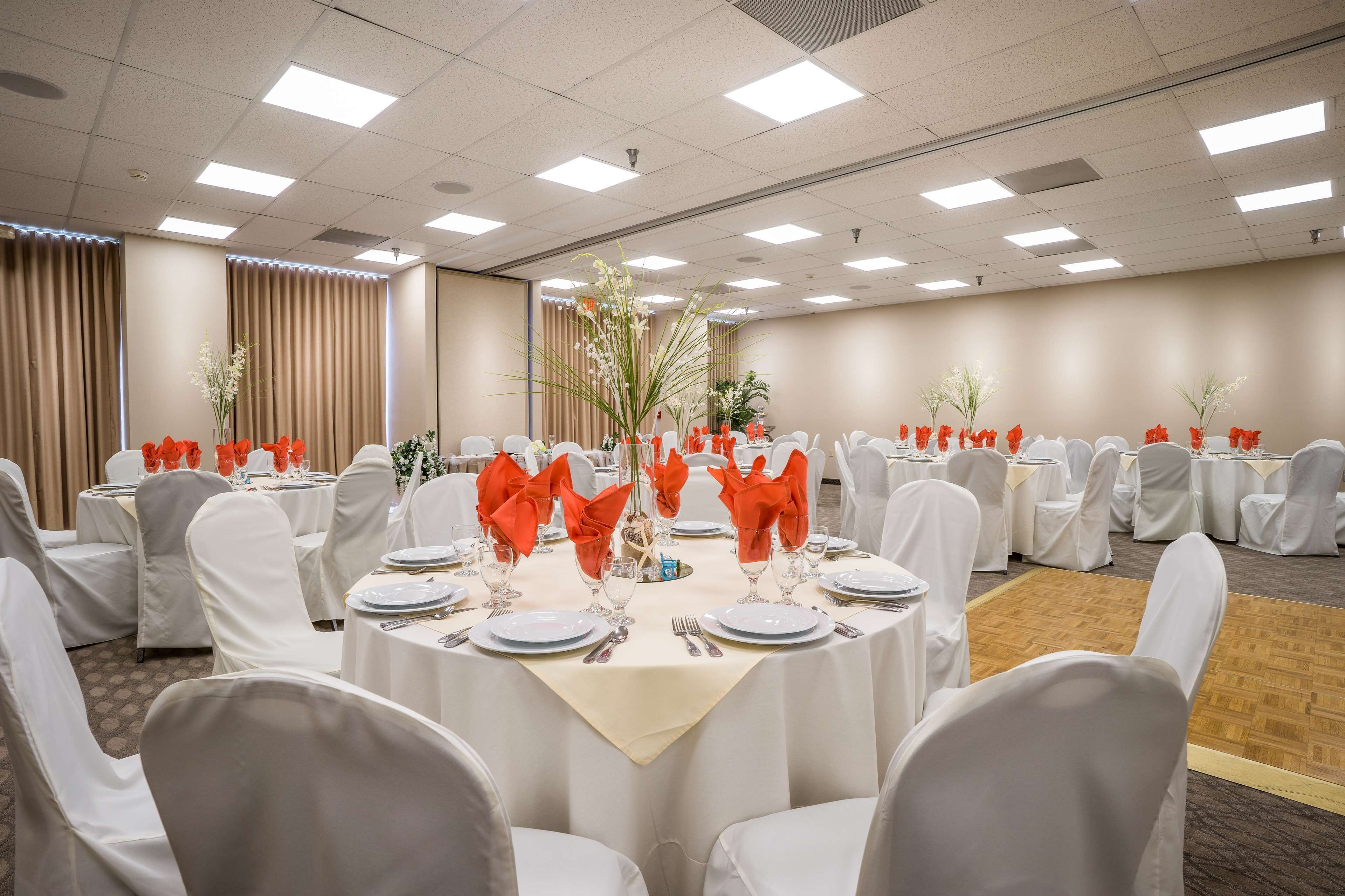 A conference room with round tables, white chairs, and red napkins.
