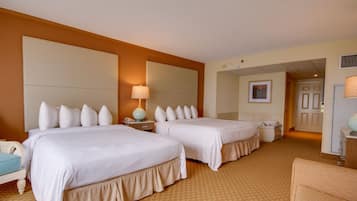 A hotel room with two beds, a nightstand, a lamp, and a door leading to another room.