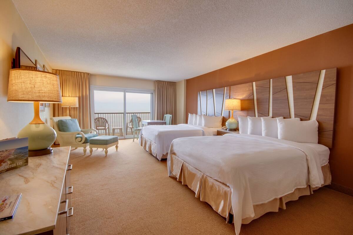 Une chambre d’hôtel avec deux lits, un bureau avec une lampe, une chaise et une vue sur l’extérieur.