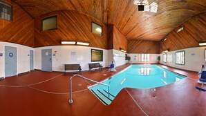 An indoor swimming pool with wooden ceiling and walls, multiple doors, and benches.