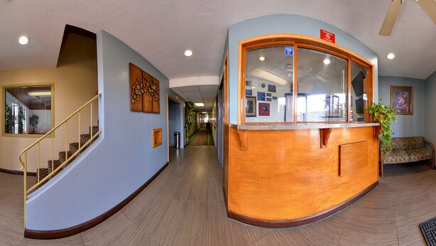 A reception area with a wooden counter, a glass door leading outside, and a staircase with a yellow railing.