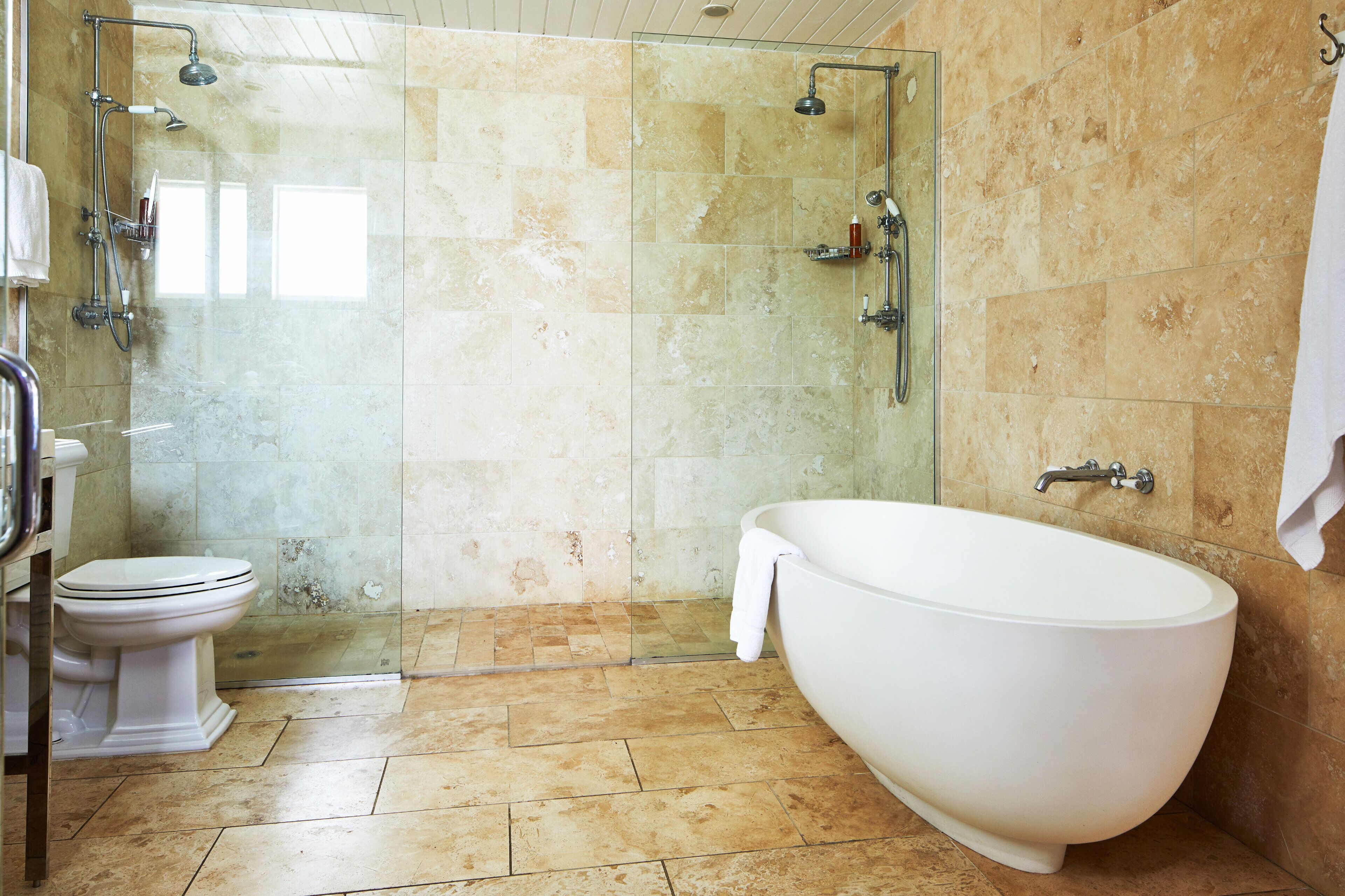 A bathroom with a glass-enclosed shower, a freestanding bathtub, and a toilet.