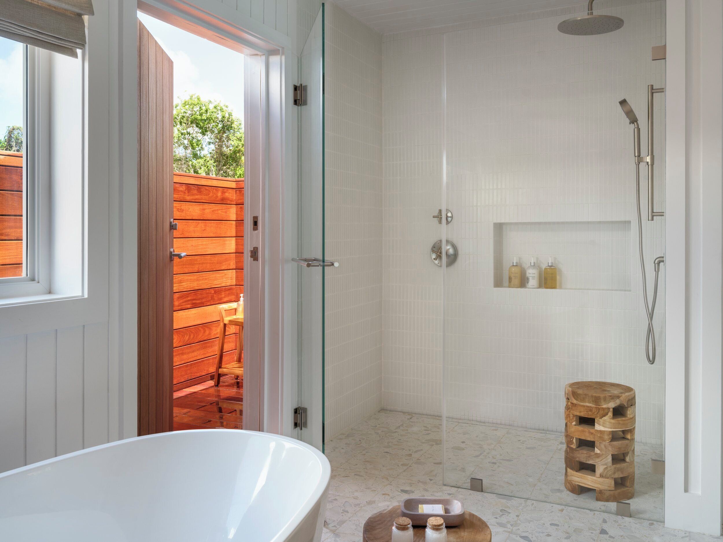 A modern bathroom with a freestanding bathtub, a glass-enclosed shower, and a wooden stool.