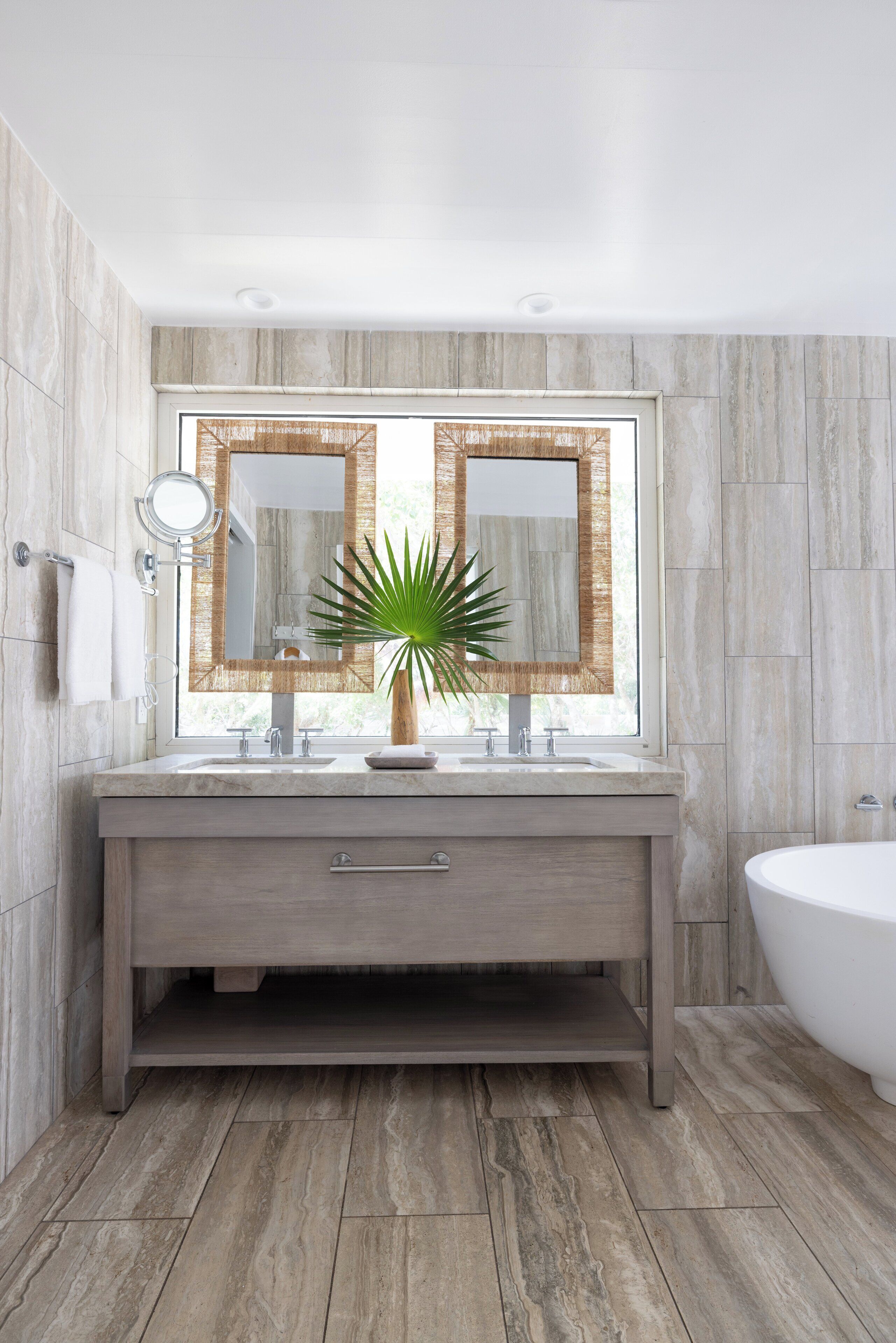 Un baño moderno con un espejo grande, un lavamanos y una bañera.