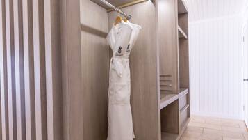 A modern, well-lit walk-in closet with wooden shelving and a hanging robe rack.