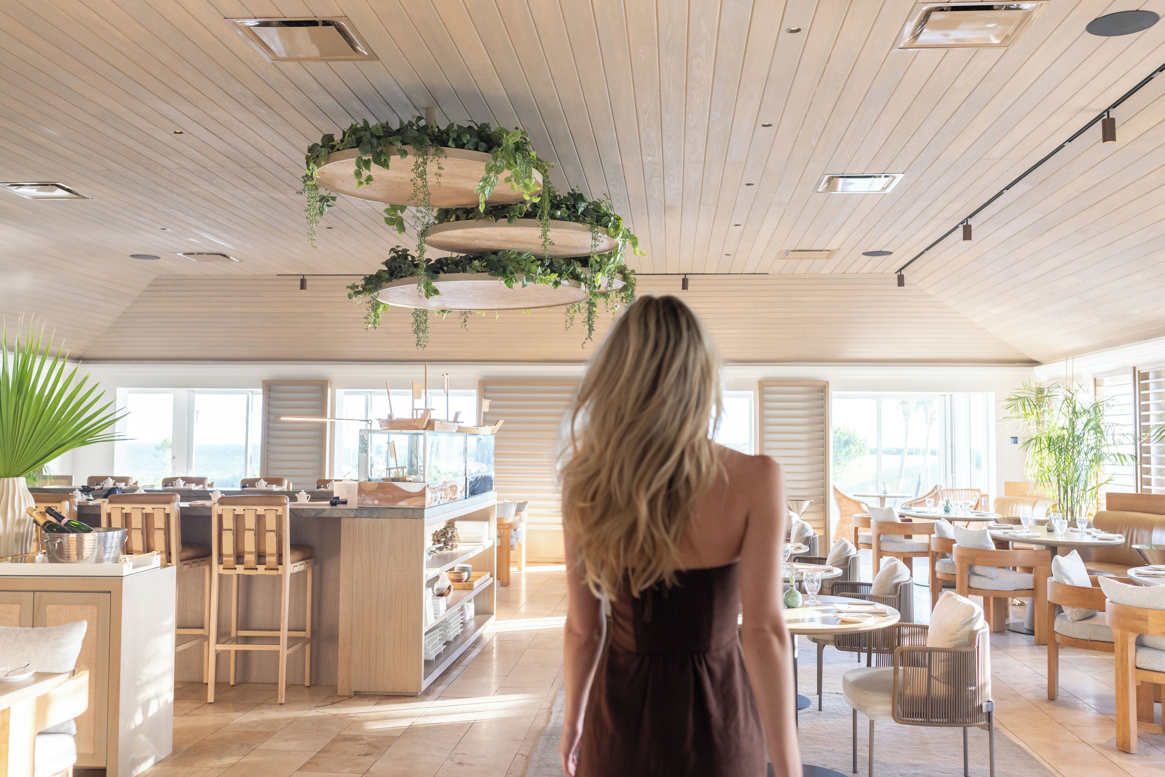 A spacious, well-lit interior with wooden flooring, a central bar area, and multiple seating arrangements.