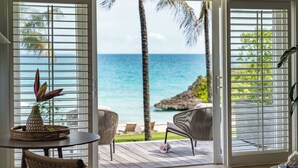 A room with a view of the ocean, wicker furniture, and a tropical plant. - The Cove Eleuthera (Gregory Town)