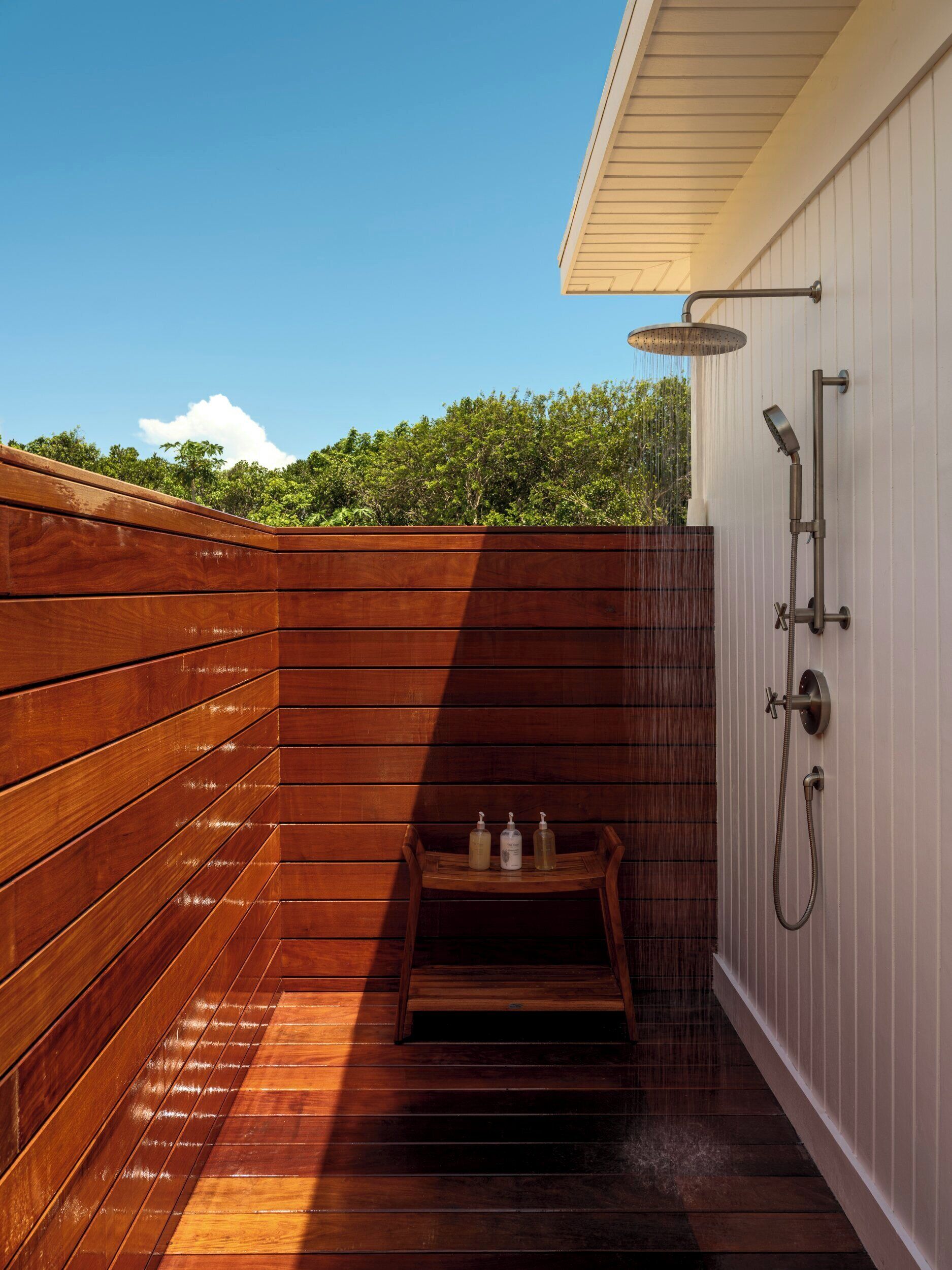 Una terraza de madera con zona de ducha integrada, que incluye un cabezal de ducha manual y un grifo empotrado.