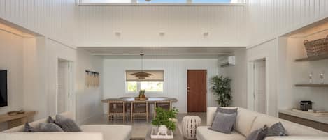 A spacious living room with high ceilings, a ceiling fan, and a large window providing natural light.