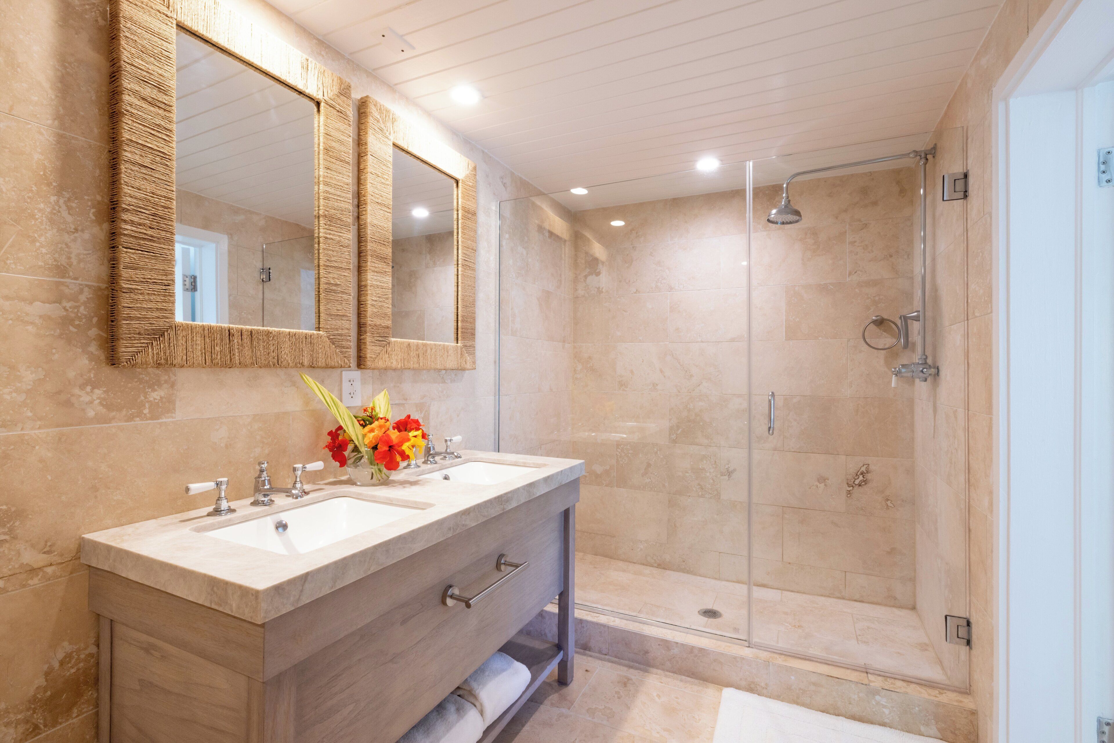 A modern bathroom with a double sink vanity, a large mirror, and a walk-in shower.