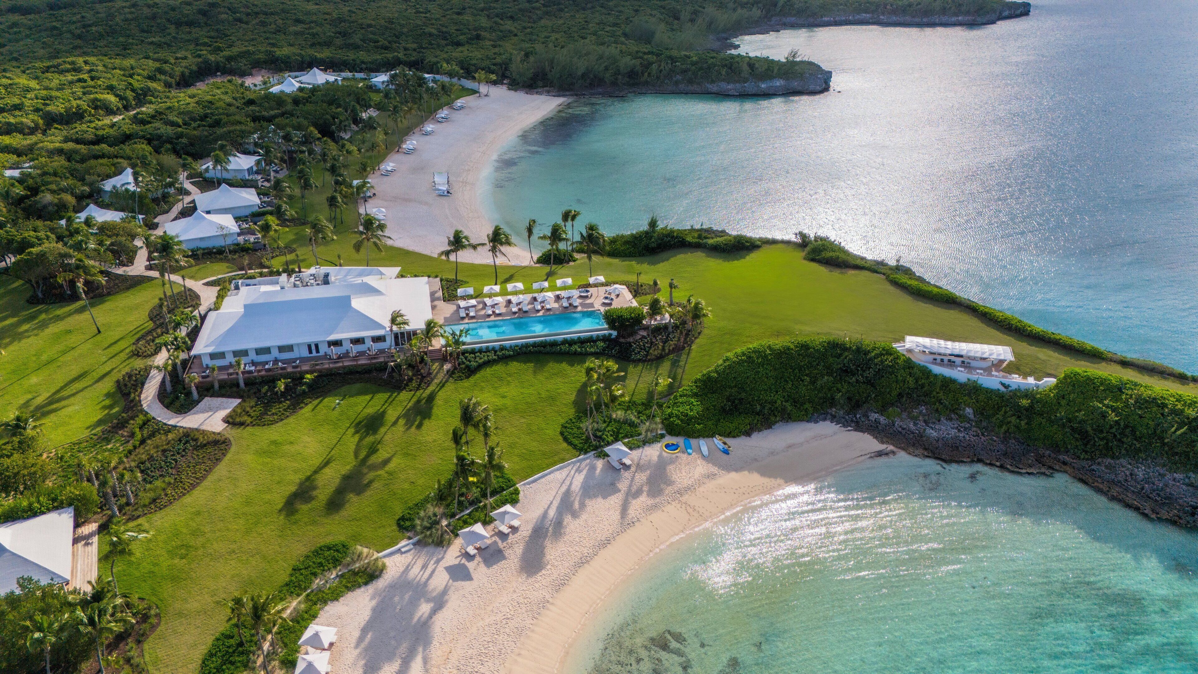 An aerial view of a resort with a swimming pool, beach, and ocean.