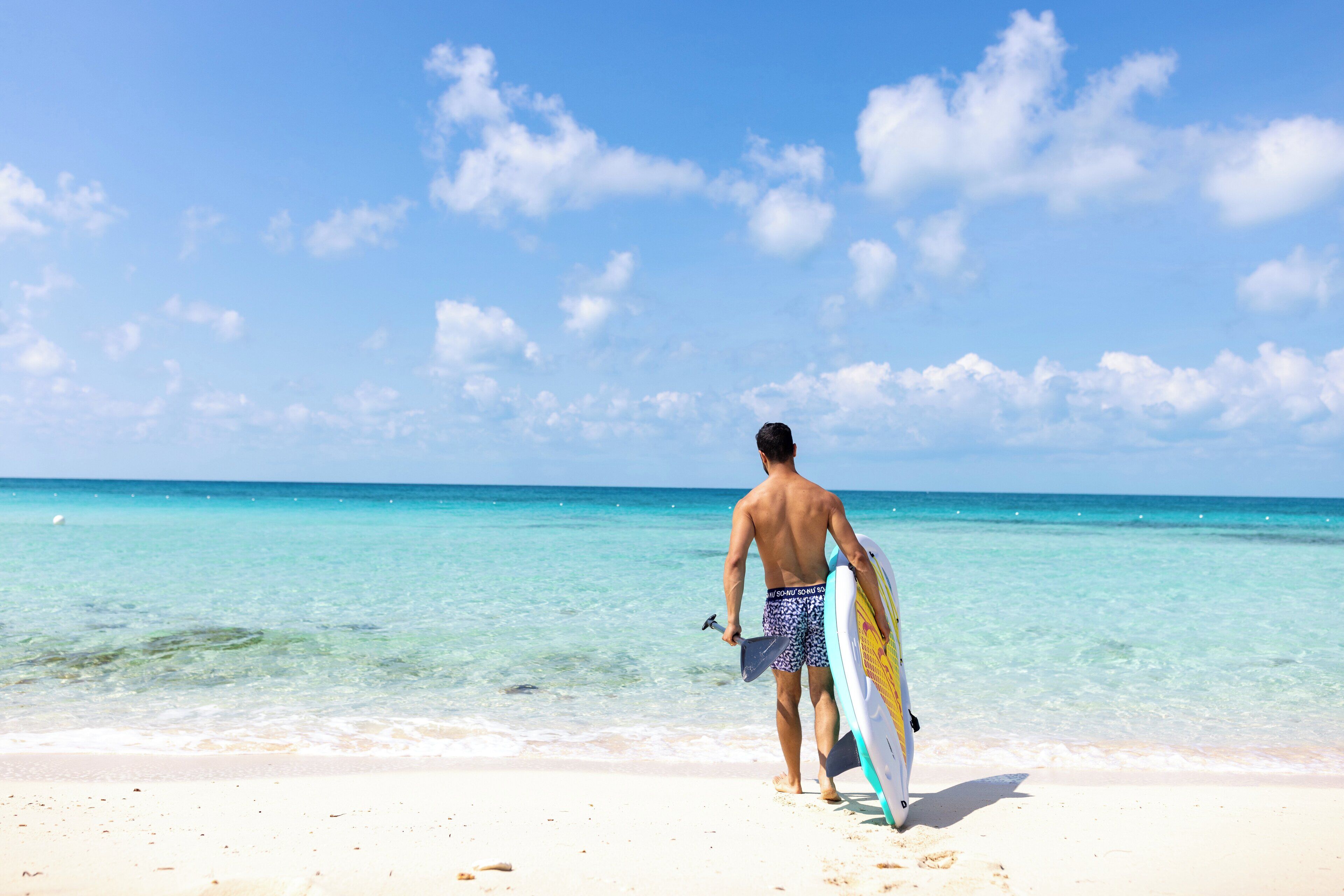 A man walking on a beach with a surfboard.