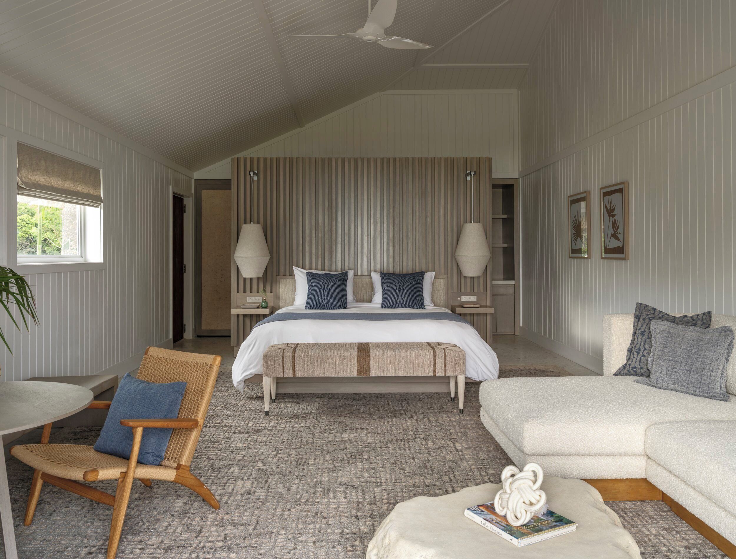 A bedroom with a bed, bedside tables, a chair, a sofa, and a ceiling fan.