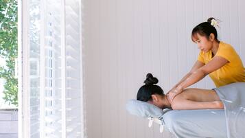 A massage therapy session in a room with a window and blinds.