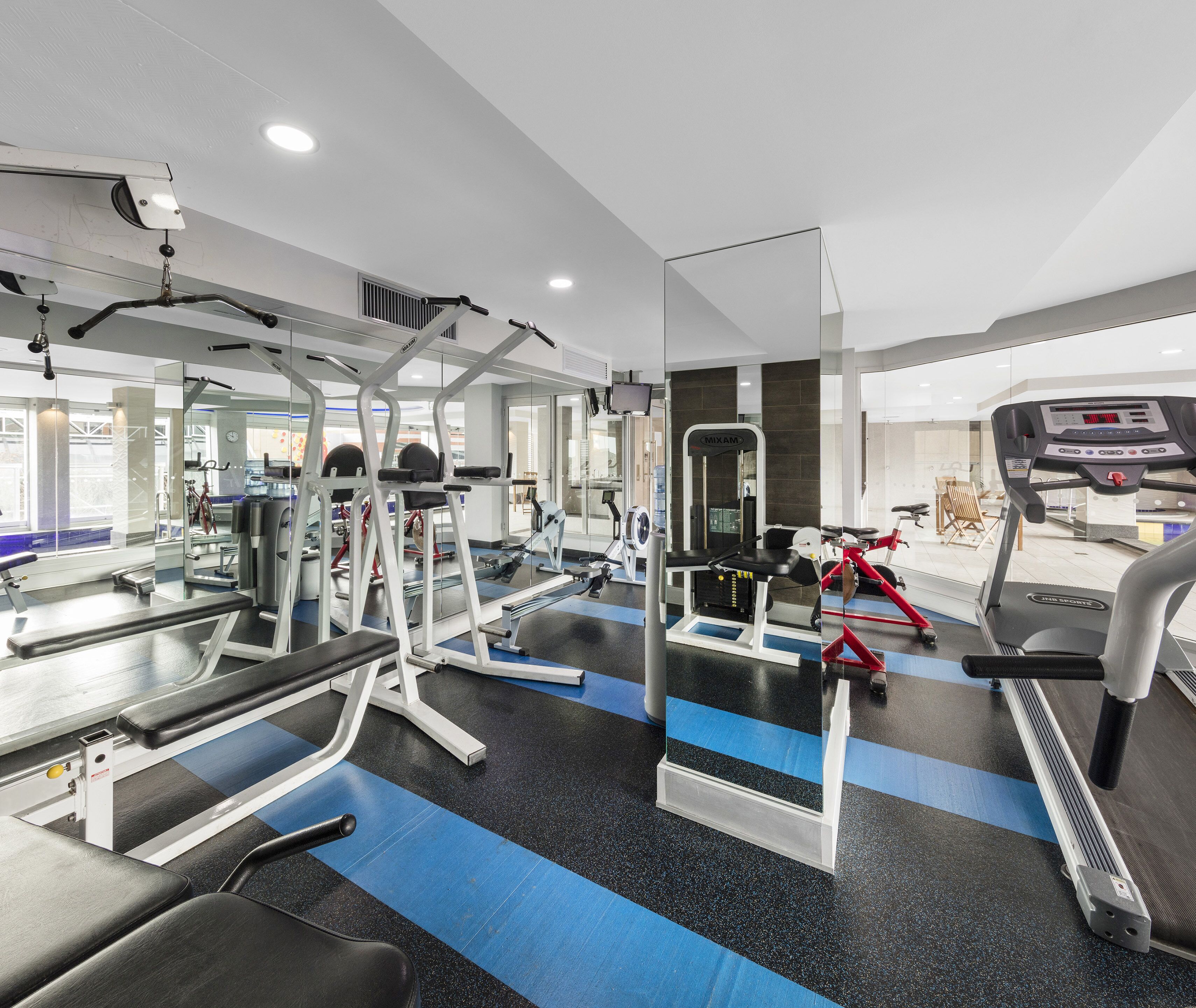 A modern gym with various exercise equipment, including treadmills, stationary bikes, and weight machines.
