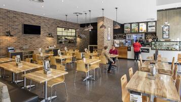 A cafe interior with brick walls, wooden tables, and hanging pendant lights.