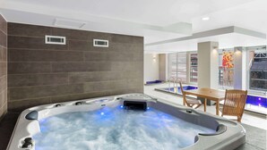 Una bañera de hidromasaje moderna en el interior, con vista a una piscina y un comedor.