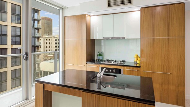 Una cocina moderna con encimera negra, armarios de madera y vistas de la ciudad a través de un ventanal.