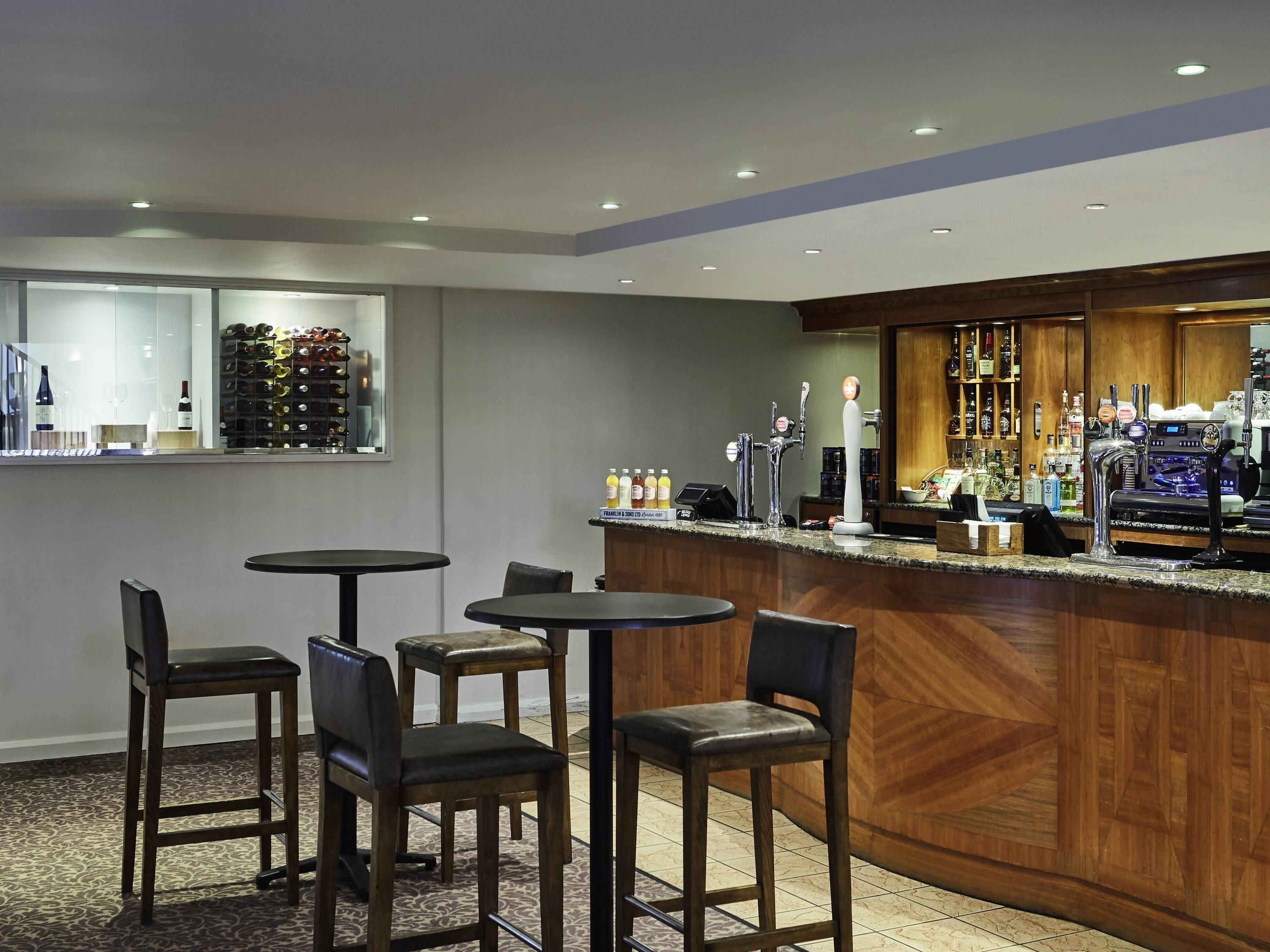 A bar area with multiple seating options, a wine rack, and a variety of bottles and glasses.