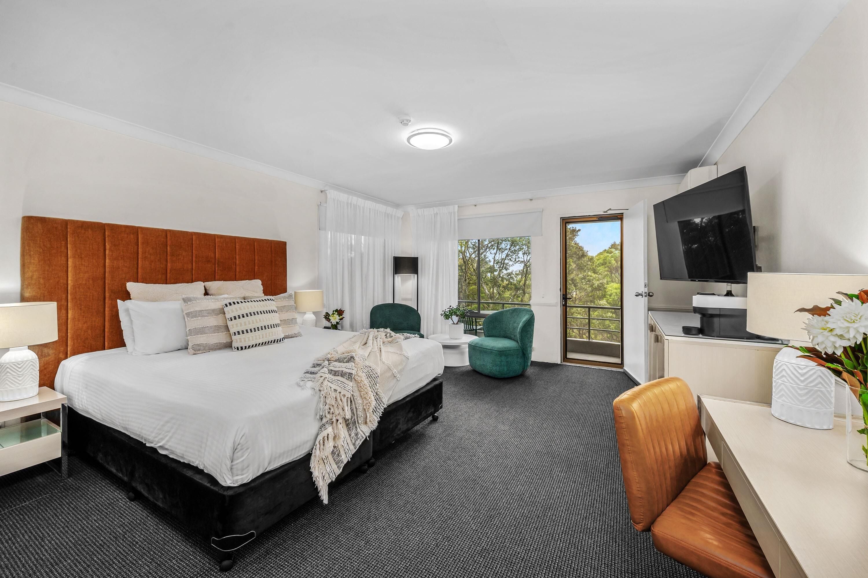 Une chambre d’hôtel équipée d’un lit, d’un bureau, d’une chaise, d’une télévision et offrant une vue sur l’extérieur.