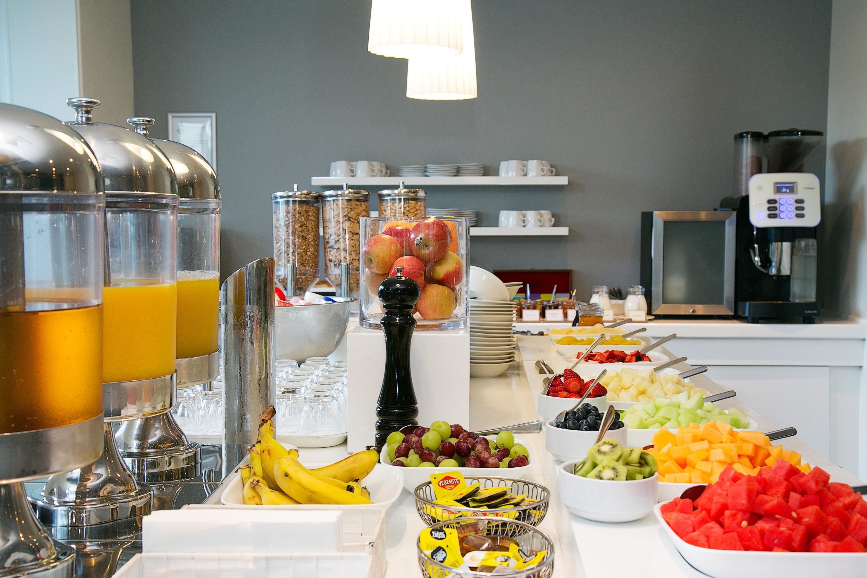 A buffet with various fruits, vegetables, and beverages.