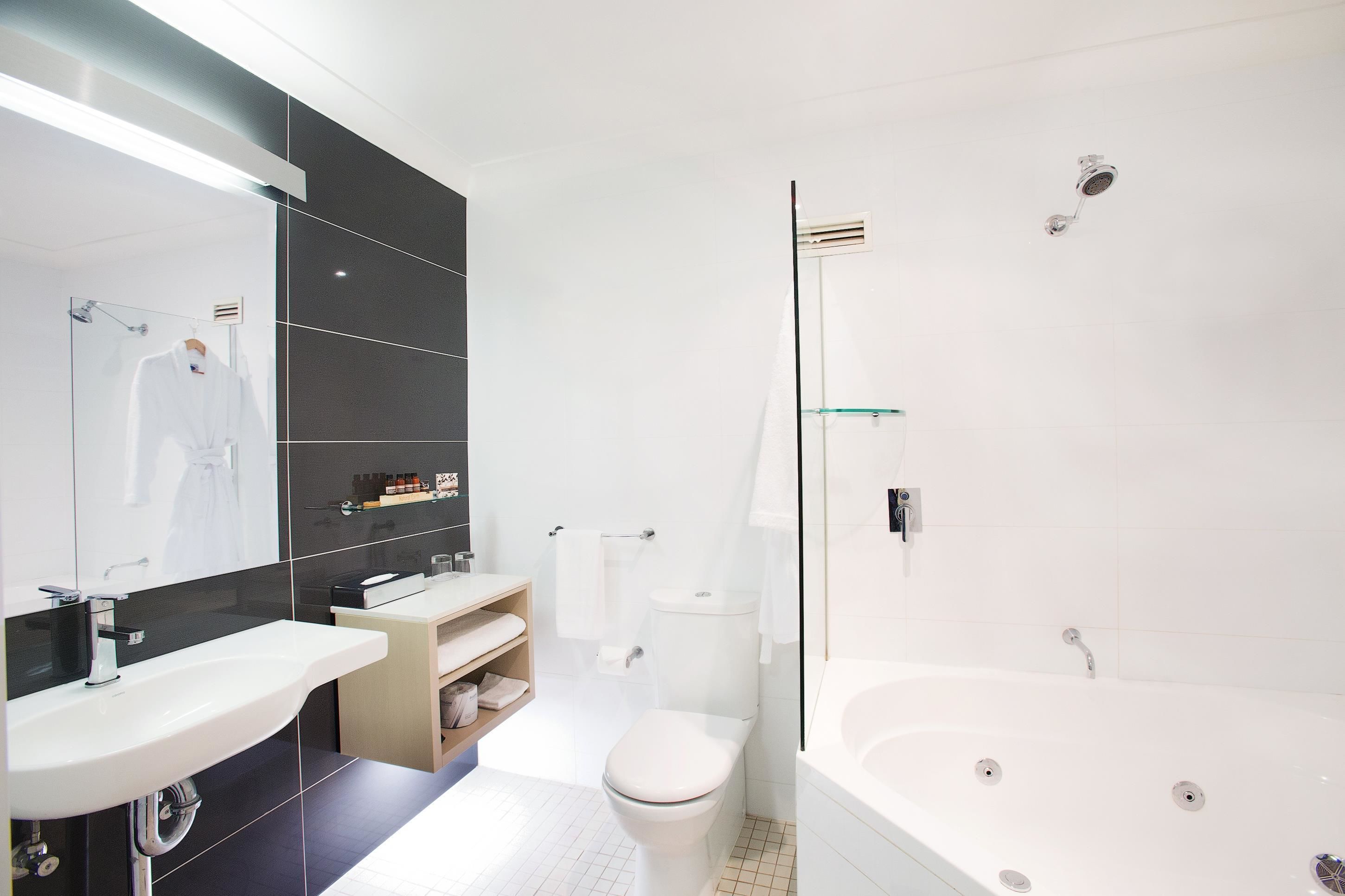 Un baño moderno con una bañera blanca grande, una zona de ducha separada y un tocador con espejo.