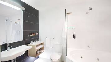Un baño moderno con una bañera blanca grande, una zona de ducha separada y un tocador con espejo.