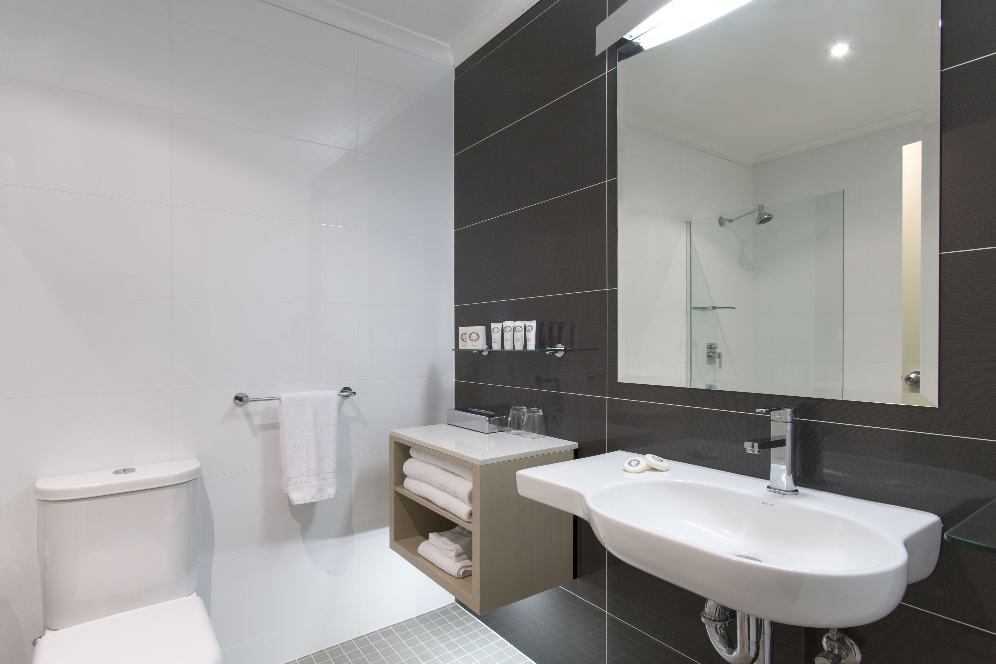 Un baño moderno con inodoro, lavamanos y espejo.