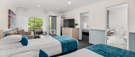 A hotel room with two beds, a desk, a chair, a TV, and a bathroom.