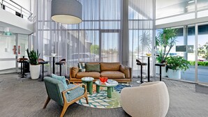 A modern lobby with a leather sofa, round tables, and potted plants. - Best Western Plus Apollo Hotel Newcastle (Charlestown)