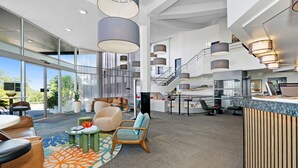 A spacious hotel lobby with a high ceiling, large windows, and a central staircase. - Best Western Plus Apollo Hotel Newcastle (Charlestown)
