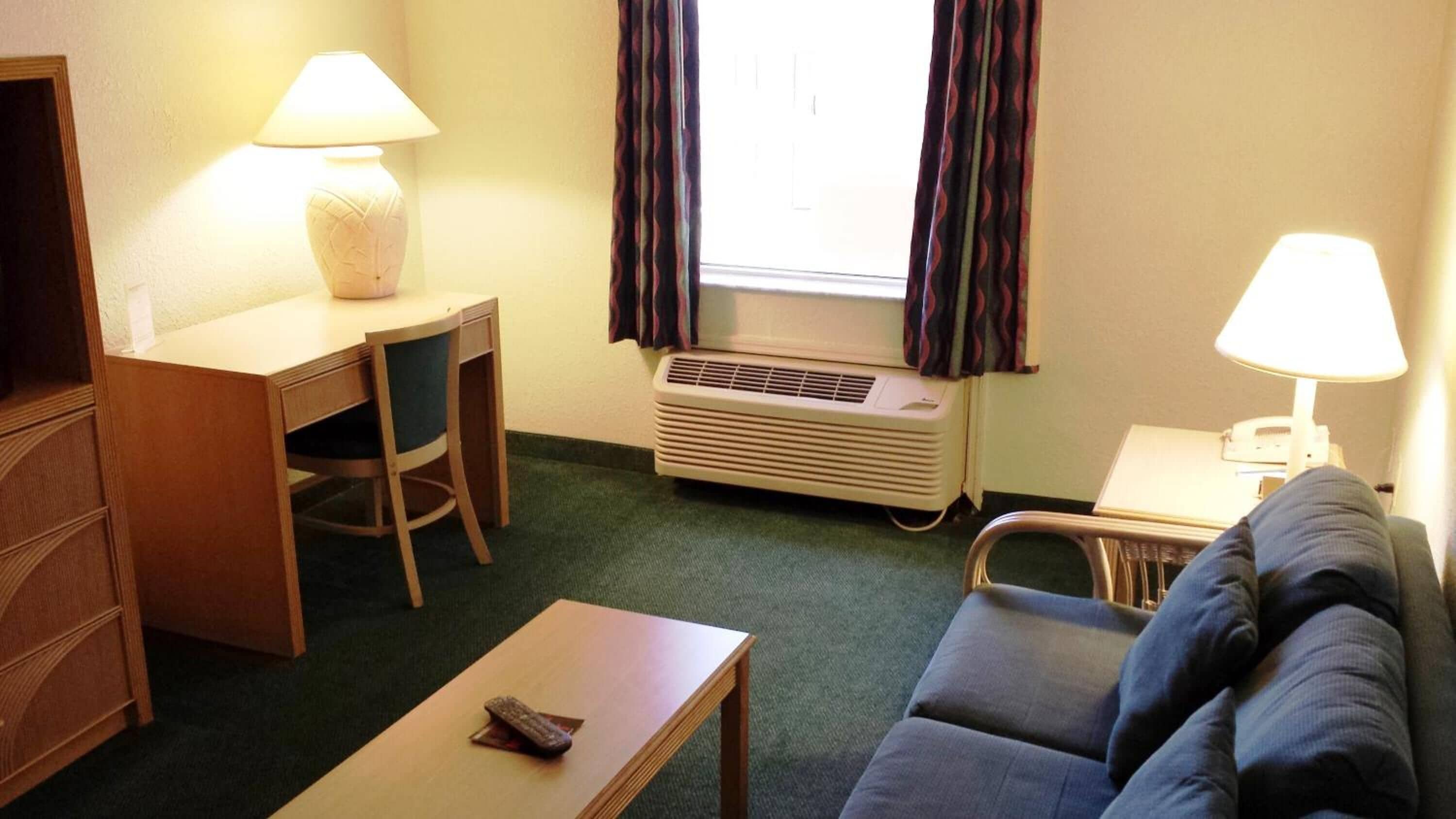 Une chambre d’hôtel équipée d’un bureau, d’une chaise, d’un canapé et de deux lampes.