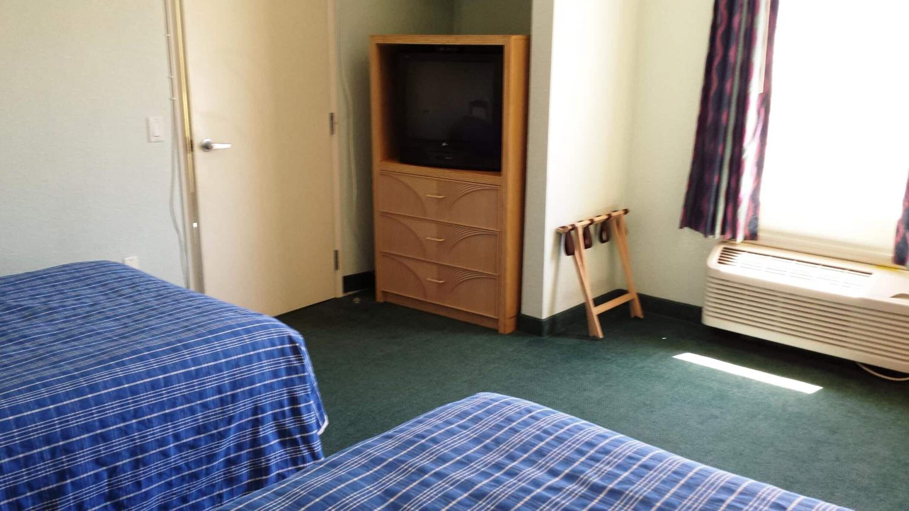A room with two beds, a wardrobe, a heater, and a window with curtains.
