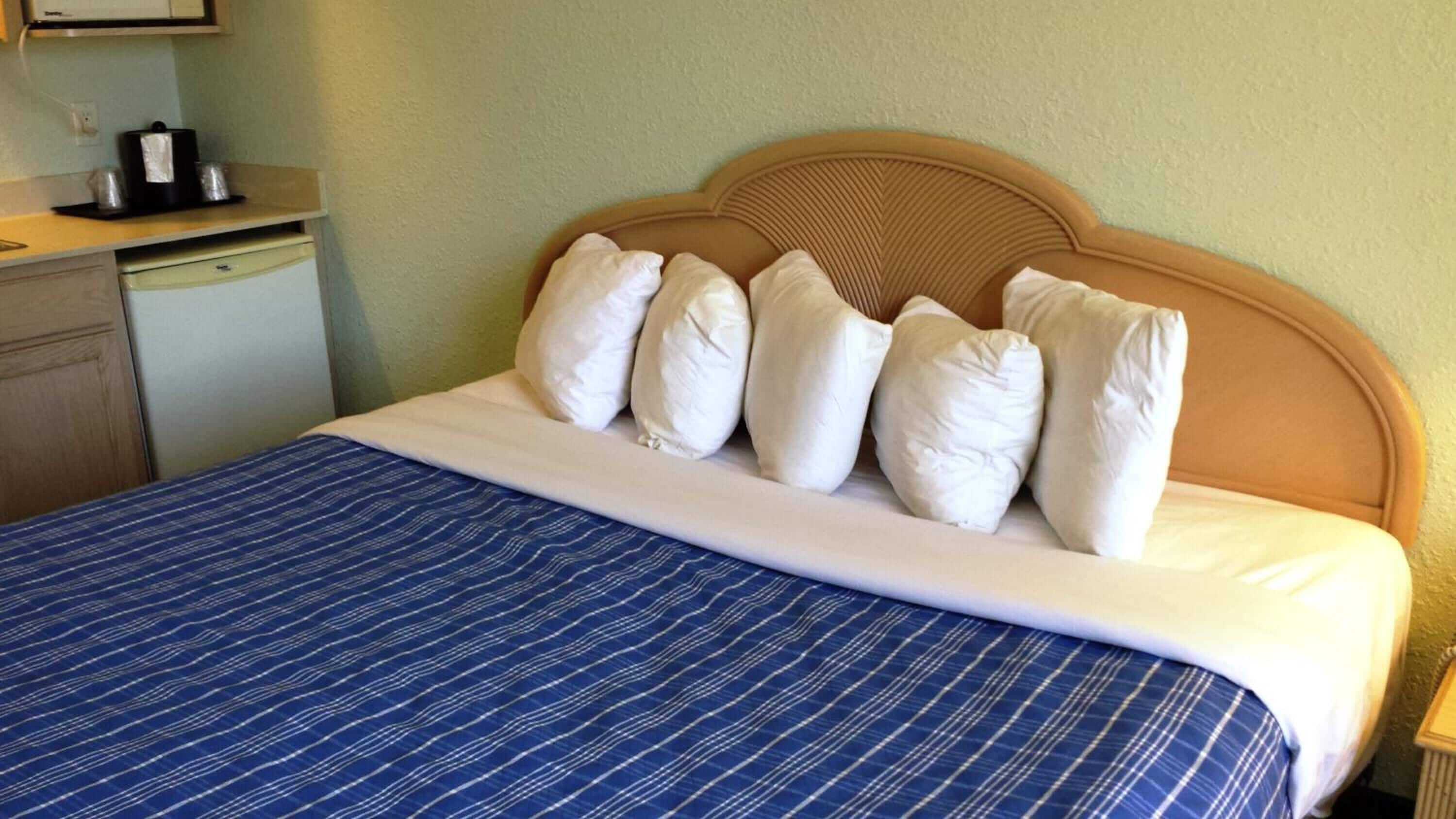 Una habitación de hotel con una cama, cabecera de madera y colcha a rayas azules.