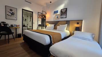 A hotel room with a large bed, a smaller bed, a desk with a chair, and a mirror.
