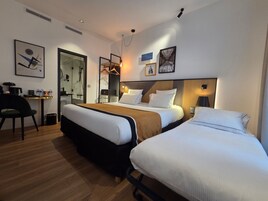 A hotel room with a large bed, a smaller bed, a desk with a chair, and a mirror.