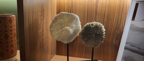 Two mushroom-shaped sculptures on black pedestals against a wooden wall.