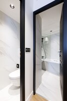 Un bagno moderno con cabina doccia in vetro, un water bianco e pareti in marmo.