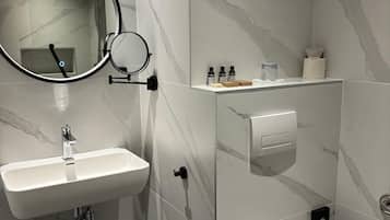 A modern bathroom with a white sink, a mirror, and a toilet.