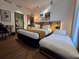 A hotel room with a bed, bedside table, chair, and a desk with a mirror.