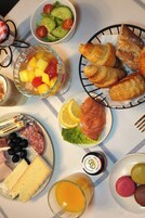 A breakfast setting with croissants, smoked salmon, cheese, and a fruit bowl.