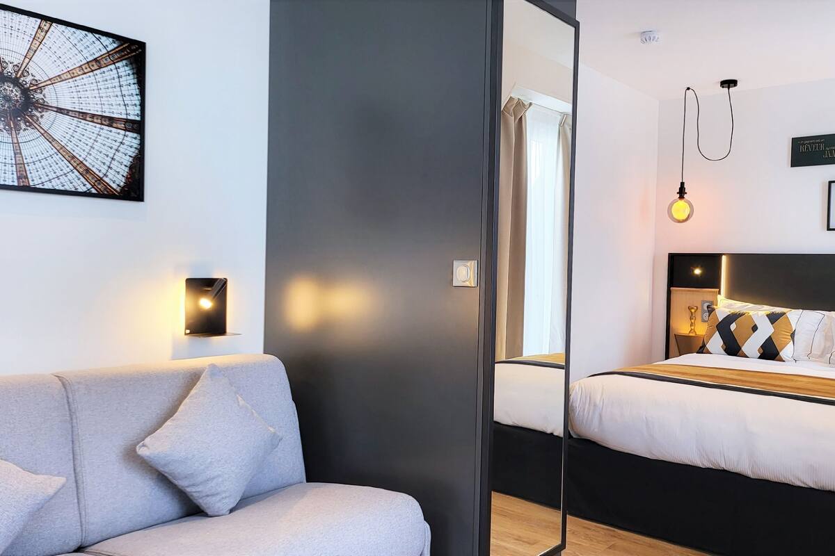 Una habitación de hotel moderna con una cama, un sofá y una obra de arte colgada en la pared.