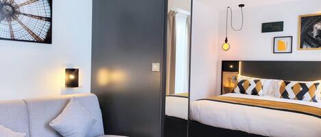 Una habitación de hotel moderna con una cama, un sofá y una obra de arte colgada en la pared.