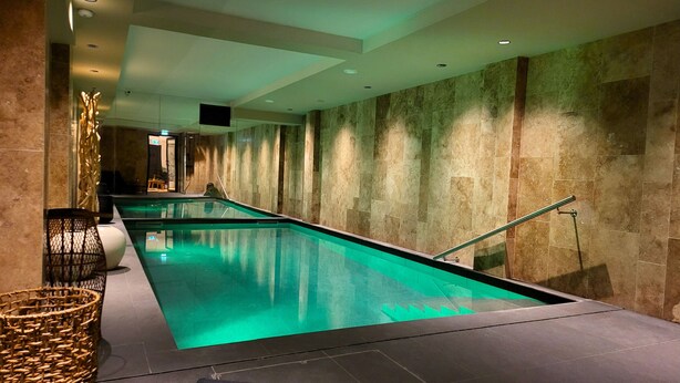 A long indoor swimming pool with clear water, surrounded by stone walls and equipped with a safety railing. - Star Champs Elysées (Paris)