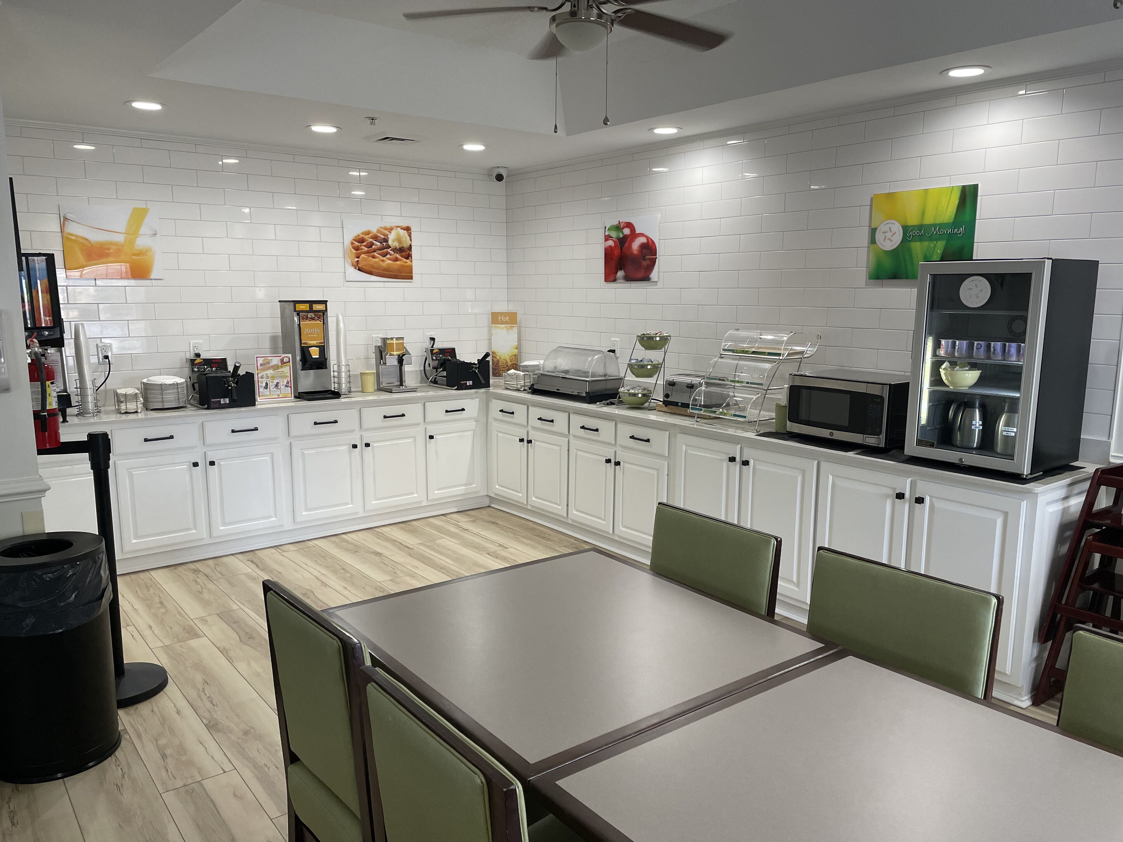 A modern kitchen with white cabinetry, a dining table, and various appliances.
