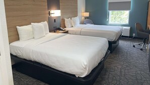 Une chambre d’hôtel avec deux lits, un bureau, une chaise et une fenêtre donnant sur un paysage agréable.