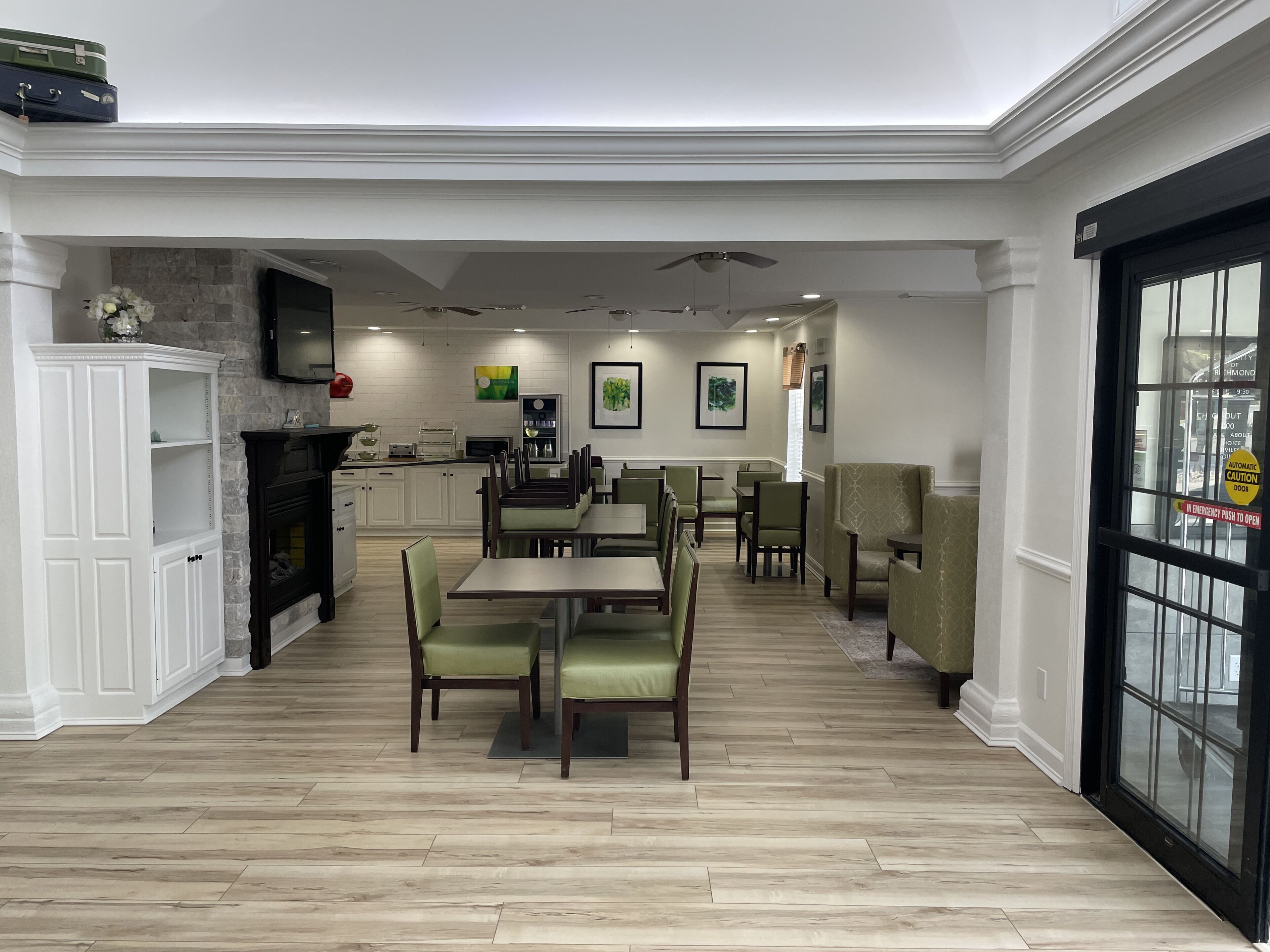 A spacious dining area with wooden flooring, green upholstered chairs, and a central table.